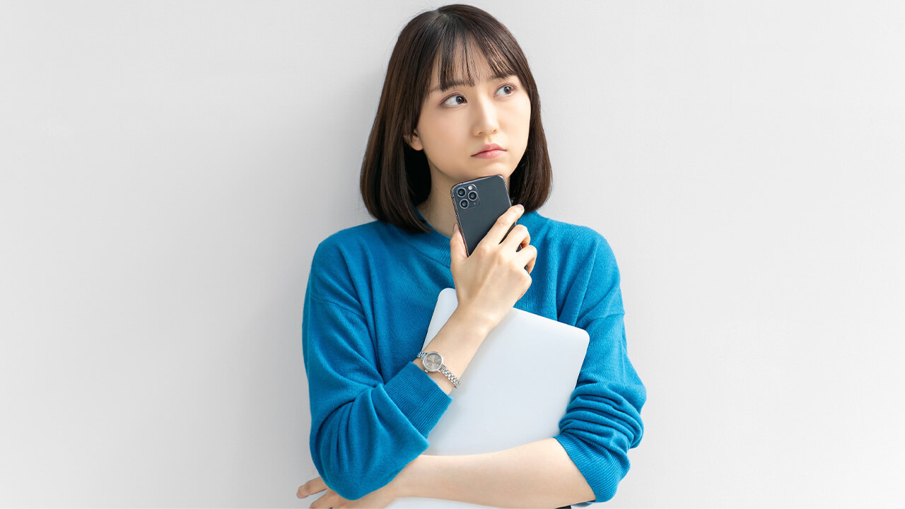 パソコンを持って悩む女性